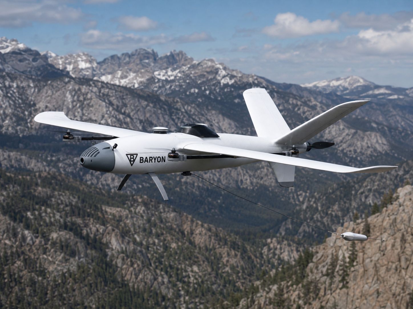 Concept render: Baryon Aerial Scout VTOL aircraft in flight over mountains with towed magnetometer deployed